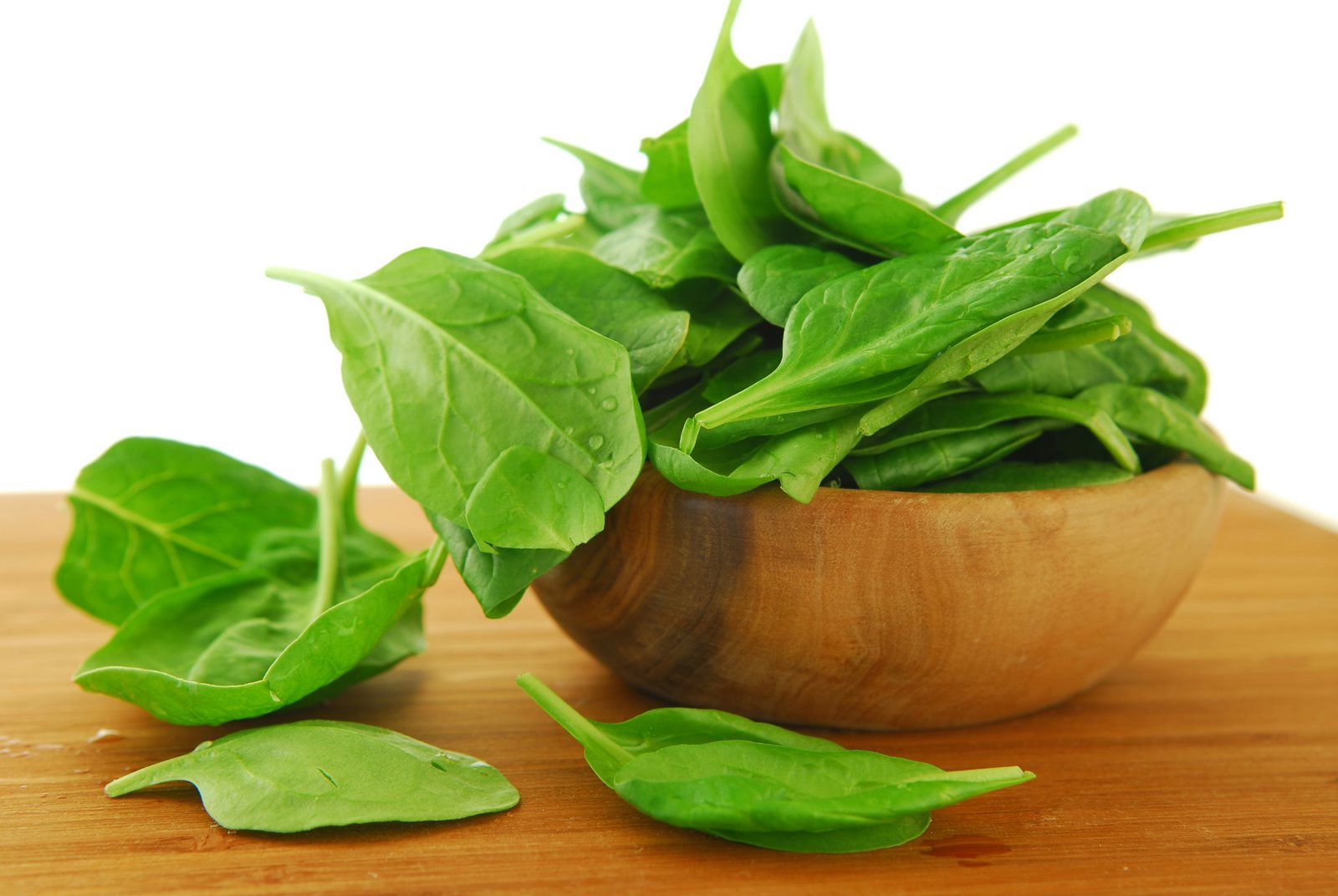 Fresh spinach iin a wooden bowl on a cutting board
